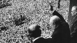 Winston Churchill greet an ecstatic crowd with his traditional two fingered Victory sign.